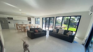 Ein geräumiger Wohnbereich mit zwei Sofas, einer Küche und großen Fenstern.