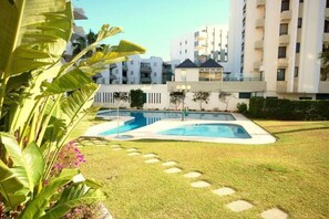 Una piscina circondata da un prato curato, con edifici moderni sullo sfondo.