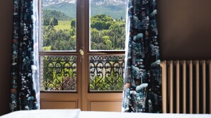 A bedroom with a large window offering a mountain view. - Superb apartment in Mexican house (Barcelonnette)