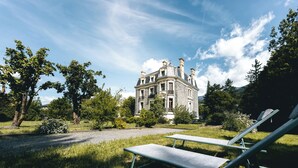 A large stone building with a symmetrical facade, surrounded by lush greenery and trees. - Superb apartment in Mexican house (Barcelonnette)