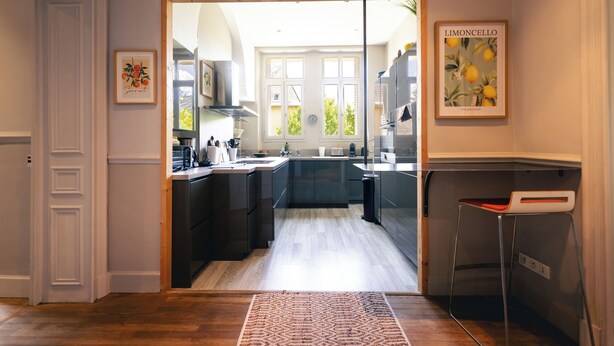 A modern kitchen with dark cabinetry, a wooden floor, and a view to the outside. - Superb apartment in Mexican house (Barcelonnette)