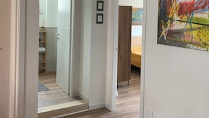 A modern interior with a wooden floor, white walls, and a large abstract painting. - Iberia 80 (Roma)