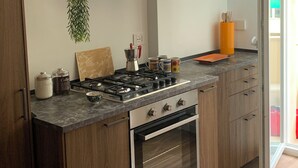 A modern kitchen with a built-in gas stove, oven, and wooden cabinets. - Iberia 80 (Roma)