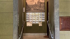 A staircase leading to a room with a cityscape mural, a bulletin board, and a wooden door. - Iberia 80 (Roma)