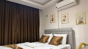 A hotel room with a bed, brown curtains, an air conditioning unit, and framed artwork on the wall. - Nativo Hotel (Antalya)