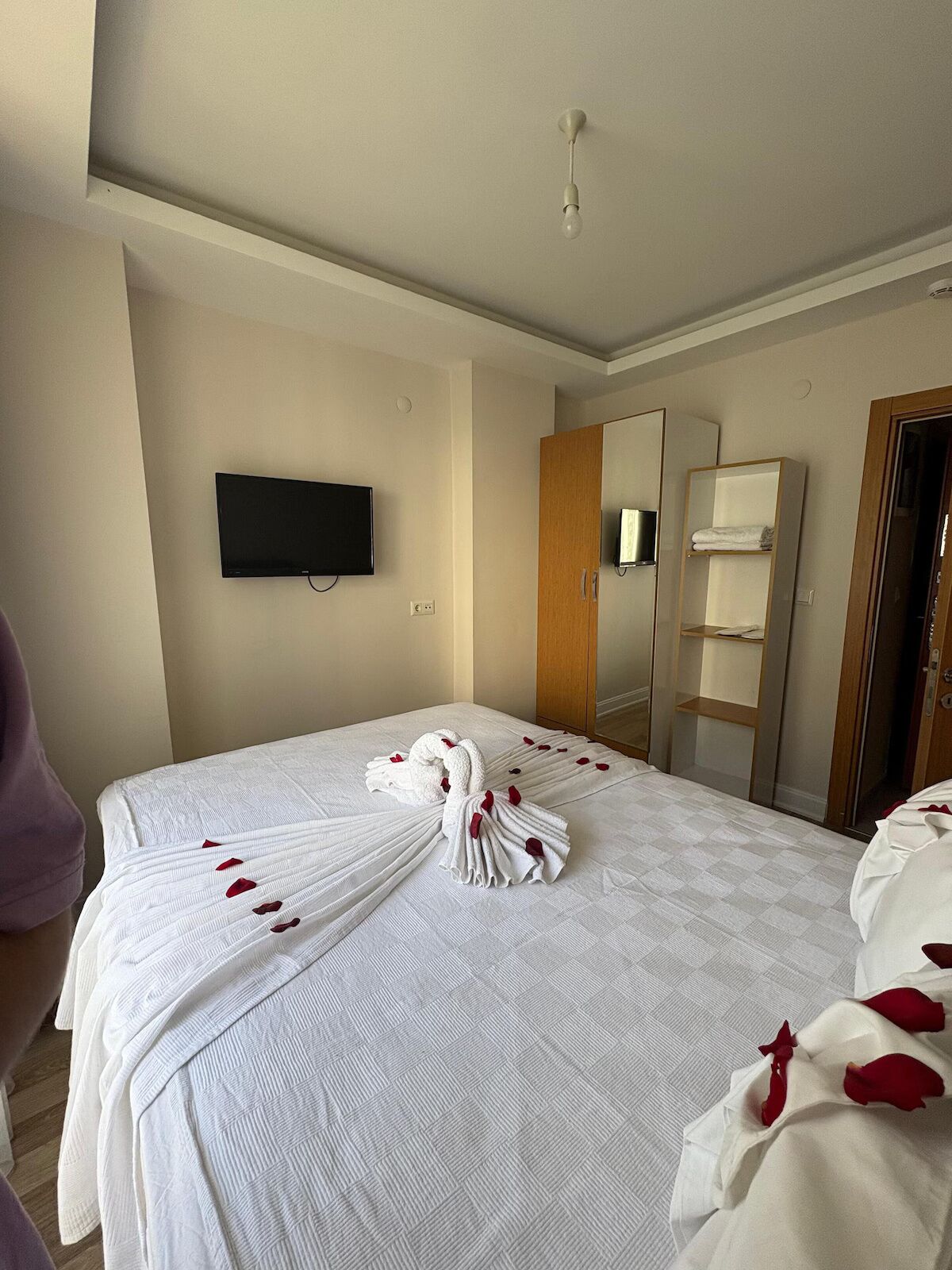 Une chambre d’hôtel équipée d’un lit, d’un téléviseur à écran plat, d’une armoire en bois et d’un miroir.