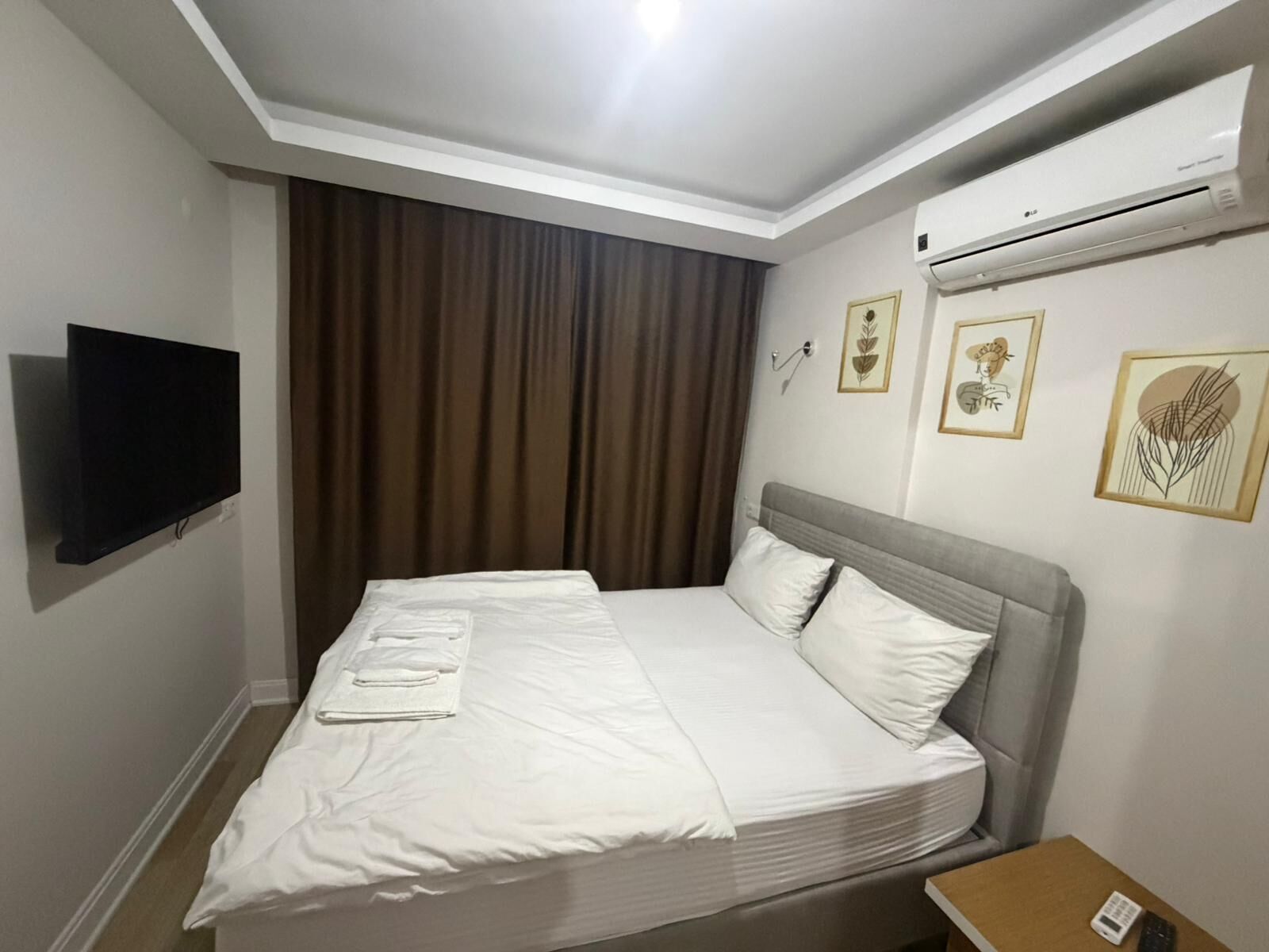Habitación de hotel con cama, televisión de pantalla plana, aire acondicionado y obras de arte en las paredes.