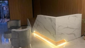 A reception area with a marble reception desk, two grey armchairs, and a wooden wall. - Nativo Hotel (Antalya)