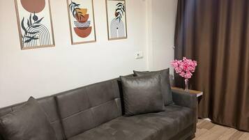 Un salon avec un canapé en cuir marron, un appareil de climatisation et trois œuvres d’art encadrées accrochées au mur.