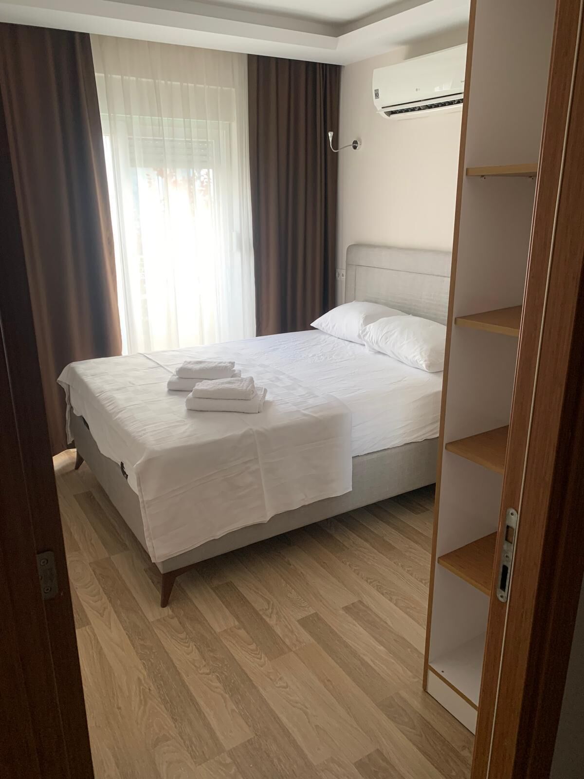 A hotel room with a bed, a wardrobe, and an air conditioning unit.