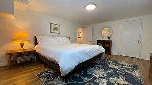 A bedroom with a bed, a nightstand, a lamp, a framed picture, a mirror, and a door. - City Vibes + Nature Trails! Relax in our comfy 2BR—perfect base for exploring Johnson City & beyond. (Johnson)