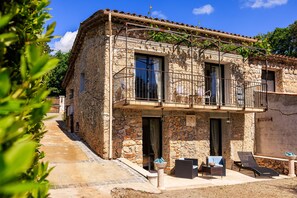 A stone building with a balcony, outdoor seating, and a clear sky.