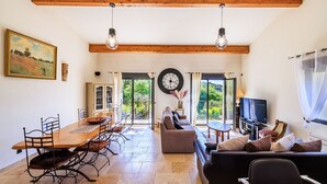 A spacious living area with a wooden dining table, sofas, and a television. - Le petit Mas - Calme 5mn from Vence (Vence)