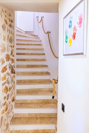 A staircase with stone walls and a handprint artwork on the wall.