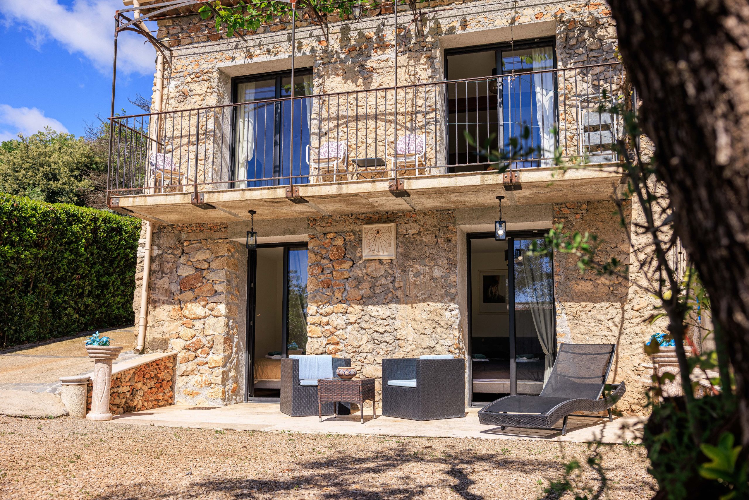 A stone building with a balcony, outdoor seating, and a view of the surrounding landscape.