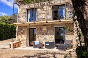 A stone building with a balcony, outdoor seating, and a view of the surrounding landscape. - Le petit Mas - Calme 5mn from Vence (Vence)