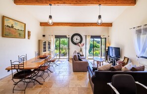 A spacious living area with a wooden dining table, sofas, and a television. - Le petit Mas - Calme 5mn from Vence (Vence)