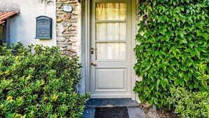 Une maison traditionnelle en pierre et en crépi, avec une porte blanche, une boîte aux lettres et une sonnette au-dessus de la porte.