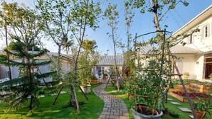 Un sentier de jardin menant à une maison dotée d’une serre et de diverses plantes.