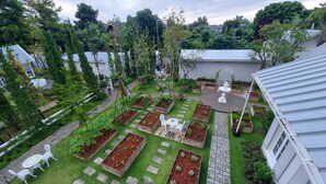 Un jardin sur le toit, avec des jardinières surélevées, une fontaine centrale et des chaises blanches.