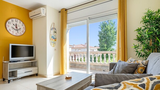 Una sala de estar con televisión, sofá, mesa de centro y un balcón con vistas.