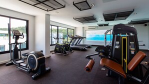 Une salle de sport équipée de machines de cardio, d’appareils de musculation et de grandes fenêtres donnant sur l’extérieur.