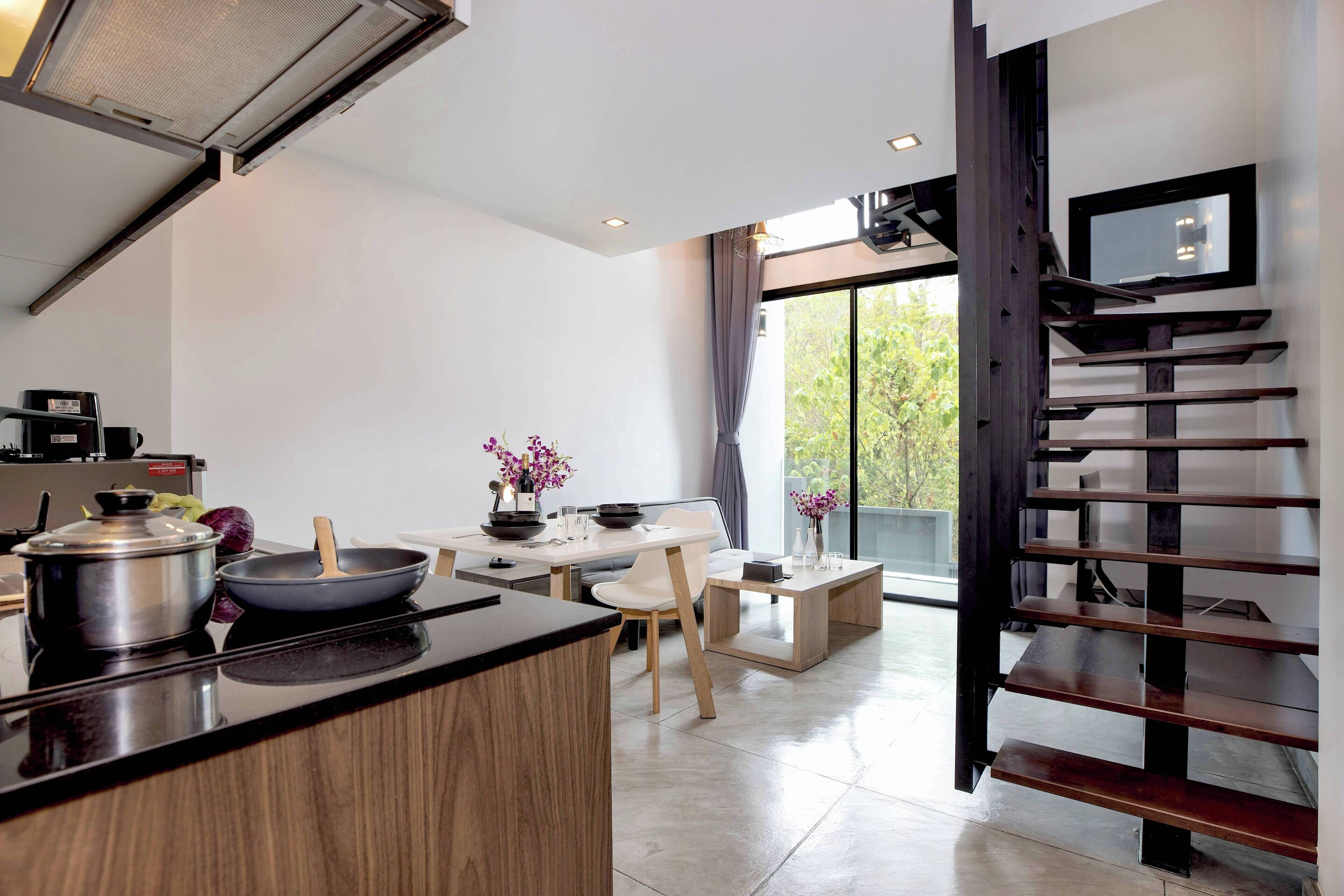 Una cocina moderna con comedor, una escalera y un ventanal amplio.