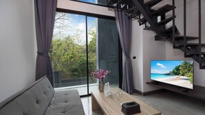Un salon moderne avec un canapé gris, une table basse en bois et un téléviseur à écran plat diffusant une scène de plage.