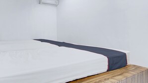 A single bed with a white mattress and a dark blue bedspread. - Hotel O Yogyakarta near Gembiraloka Zoo formerly Paddington Bear Homestay (Banguntapan)