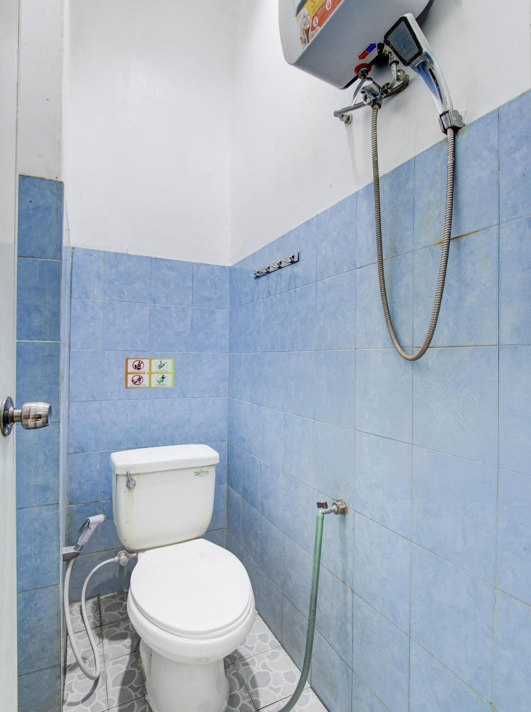 Un baño pequeño con inodoro, ducha y pared de azulejos azules.