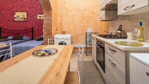 Eine kompakte Küche mit Herd, Spüle und einer kleinen Essecke mit Tisch und Stühlen.