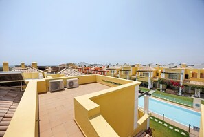 Une terrasse sur le toit équipée de climatiseurs, avec une piscine et une vue sur les autres immeubles.