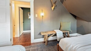 Een slaapkamer met een houten bankje, een wandlamp en een decoratieve dierenkop.