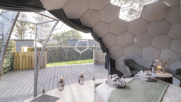 Eine moderne Decke mit sechseckigem Muster in einem Schlafzimmer mit einem großen Fenster, einem Bett mit Handtüchern und zwei Wandleuchten.