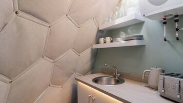 A compact kitchen with a built-in oven, a sink, and a coffee maker.