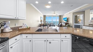A modern kitchen with white cabinets, granite countertops, and a built-in dishwasher. - San Carlos Unit 607 (Gulf Shores)
