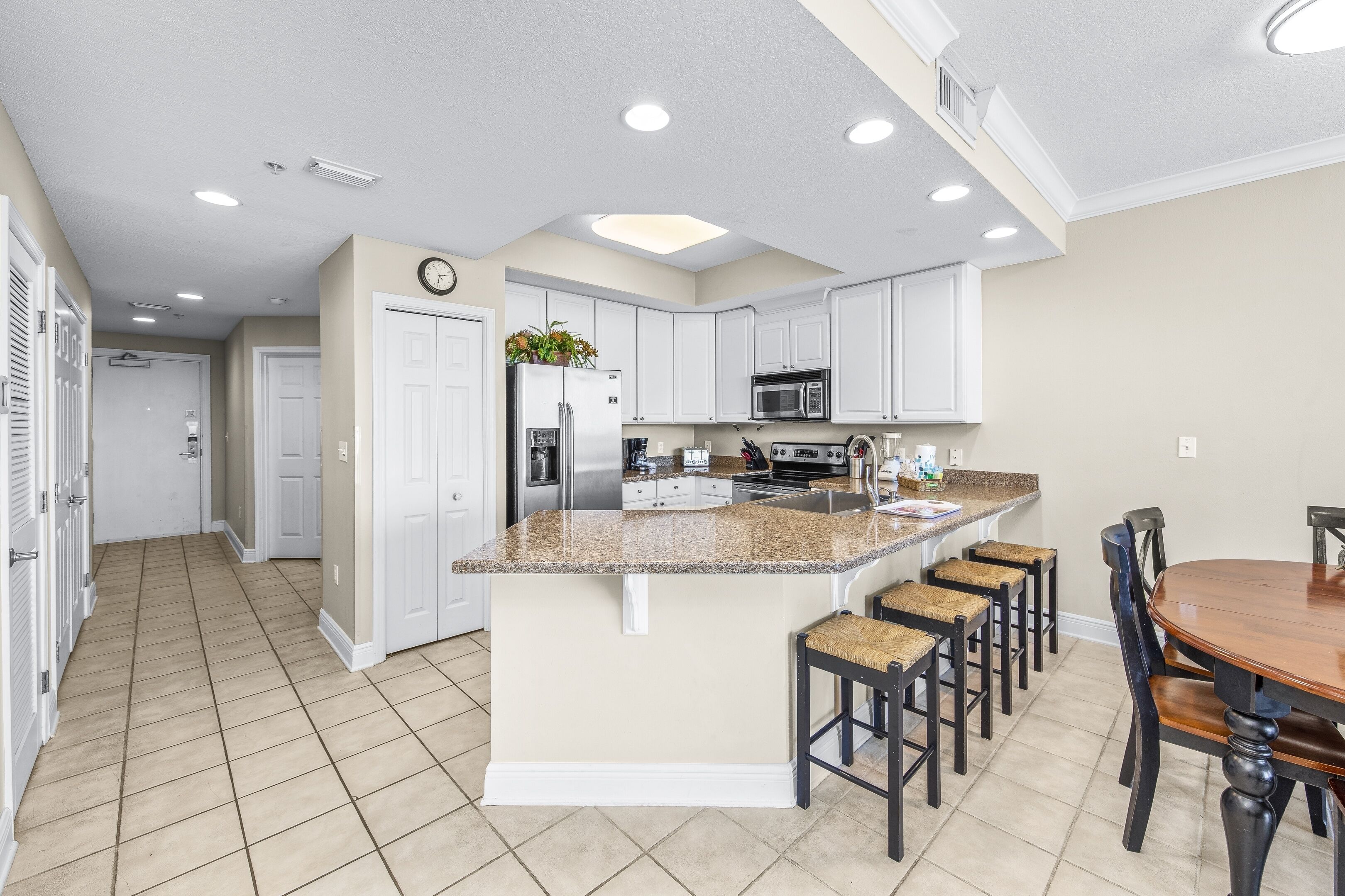 A spacious kitchen with white cabinets, a granite countertop, and a central island with bar stools.