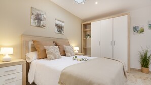 Une chambre à coucher comprenant un lit, des tables de chevet, une armoire et des œuvres d’art murales.