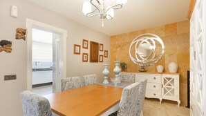 Un coin repas avec une table en bois et des chaises à motifs, un miroir décoratif et une vue sur la cuisine.