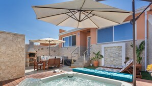 Un bain à remous, un espace salon extérieur et un coin barbecue.