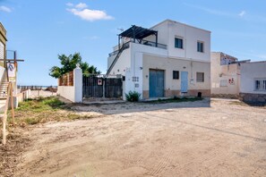 A two-story building with a gated entrance, a blue door, and a staircase leading to the upper floor. - Apartment 'Cudei Primera Línea' with Sea View, Wi-Fi and Air Conditioning (Dénia)