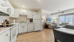 A modern kitchen with white cabinets, a built-in oven, and a dining area with a table and chairs.