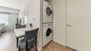 A compact kitchen with a dining area, a washing machine, and a closed door.