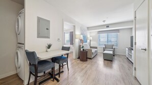 Eine moderne Wohnung mit Essbereich, einem Wohnzimmer mit Sofa und Fernseher sowie einem Waschraum mit Waschmaschine.