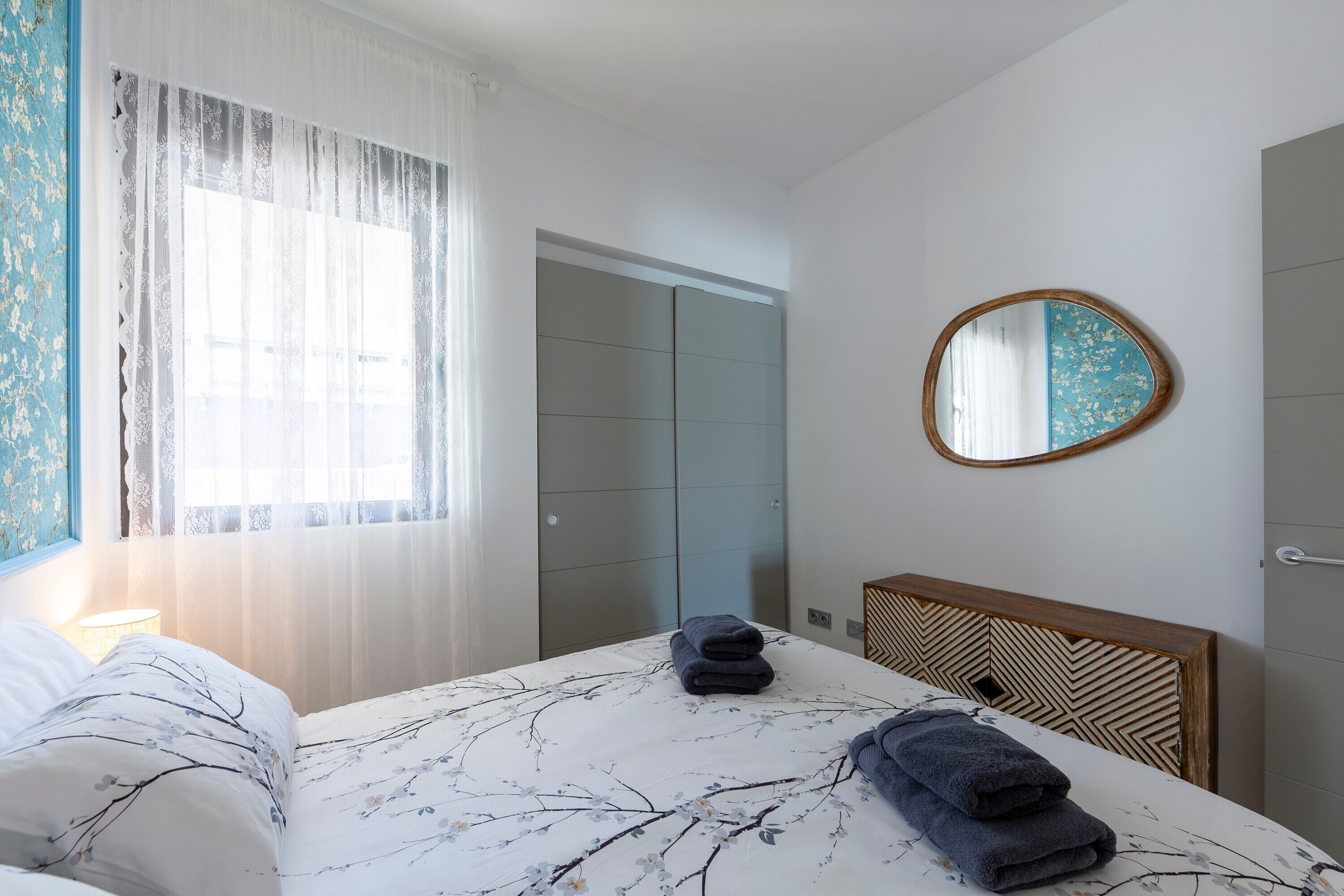 Una habitación de hotel con cama, mesita de noche, espejo y puerta.