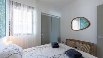 Una habitación de hotel con cama, mesita de noche, espejo y puerta.
