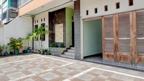 A courtyard with patterned flooring, potted plants, a staircase, and a wooden door. - Hotel O Yogyakarta near Taman Sari formerly Widitya Inn (Yogyakarta)