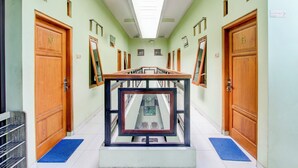 A hallway with wooden doors labeled 10 and 15, a central framed artwork, and a blue mat at the entrance. - Hotel O Yogyakarta near Taman Sari formerly Widitya Inn (Yogyakarta)