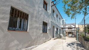 Un edificio con un letrero que dice 'LA BERNARDA', un camino pavimentado y un área cercada con una mesa y sillas.