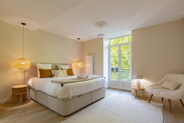 Une chambre à coucher avec un lit, des lampes de chevet, une chaise, une fenêtre et une porte.